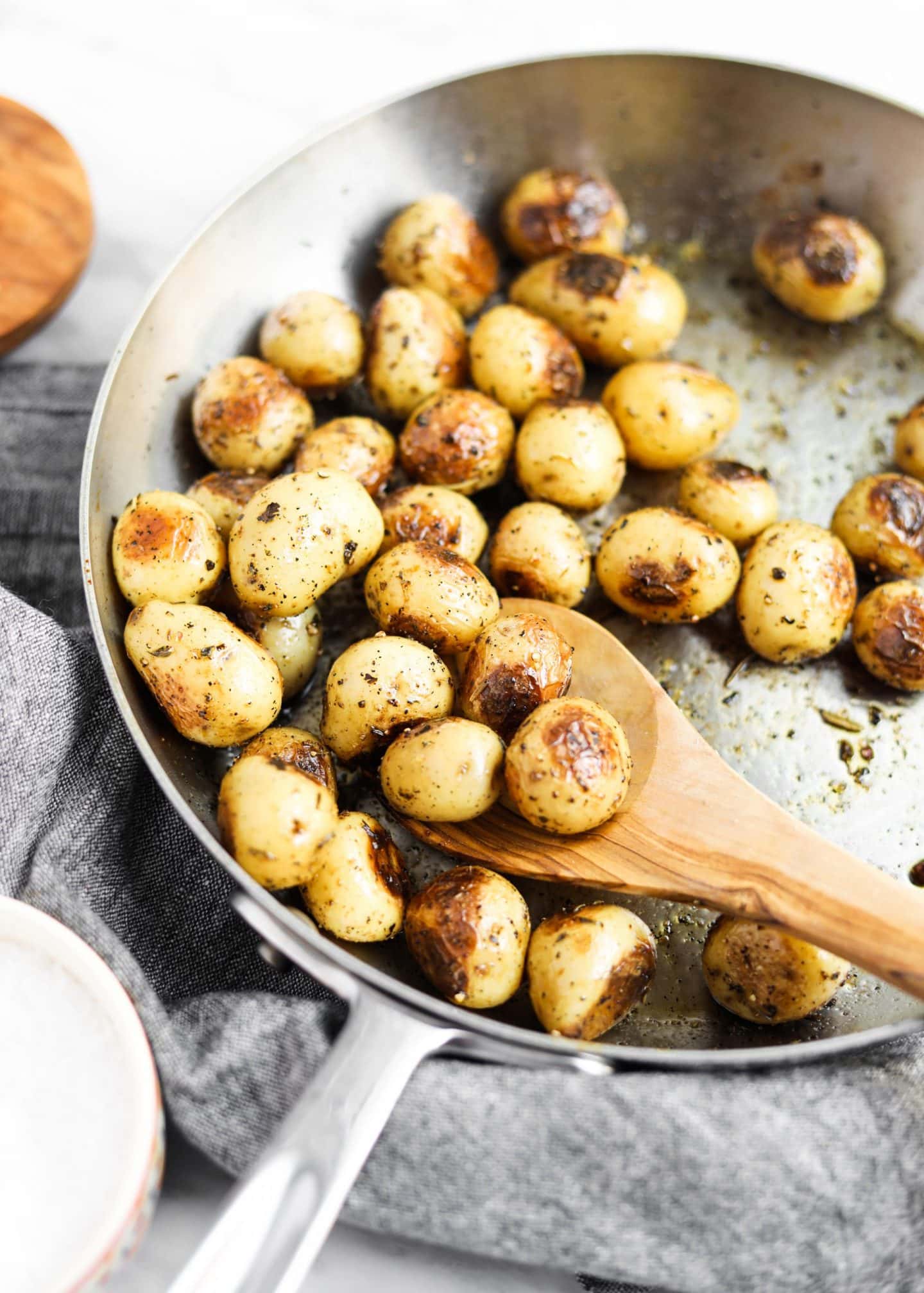 potatoes roasting in a pan with spoon and herbs