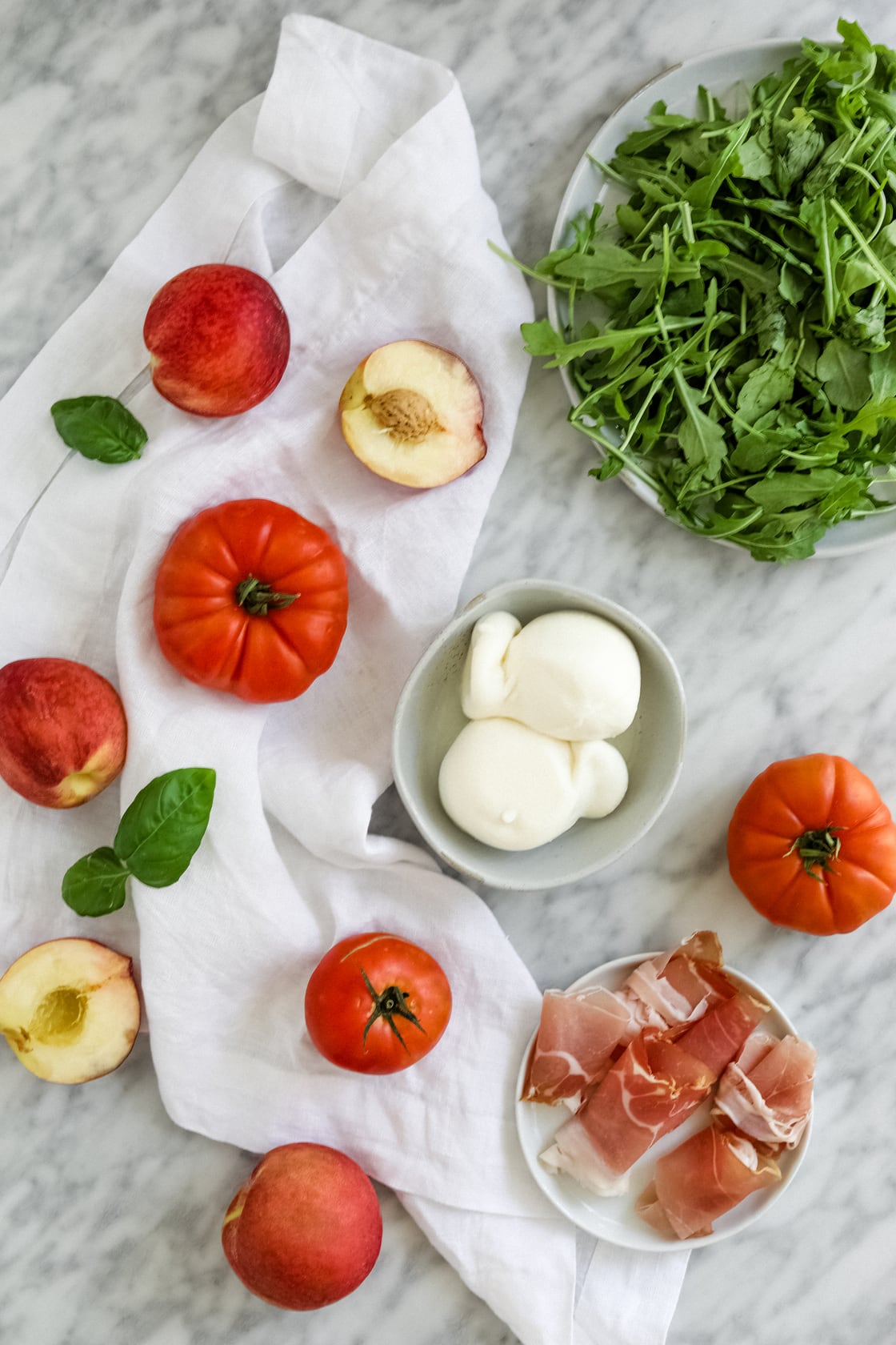 Ingredients peach arugula heirloom tomatoes prosciutto in prep bowls